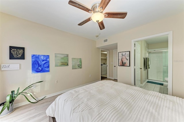 bedroom with connected bathroom, ceiling fan, light hardwood / wood-style flooring, and washer / dryer