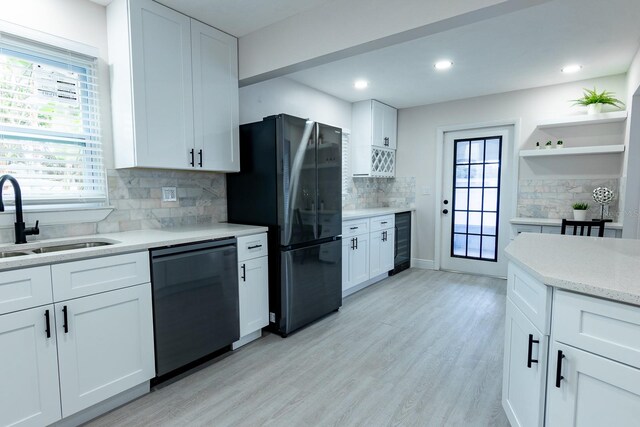 kitchen featuring tasteful backsplash, sink, black appliances, light hardwood / wood-style floors, and white cabinetry