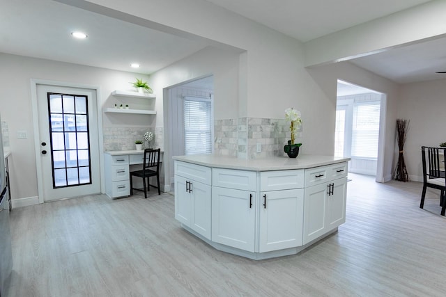 kitchen featuring backsplash, white cabinets, a healthy amount of sunlight, and light wood-type flooring