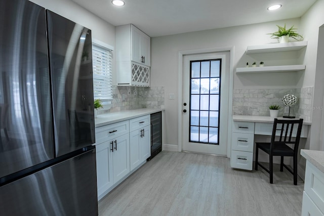 kitchen with stainless steel refrigerator, white cabinets, a healthy amount of sunlight, and wine cooler