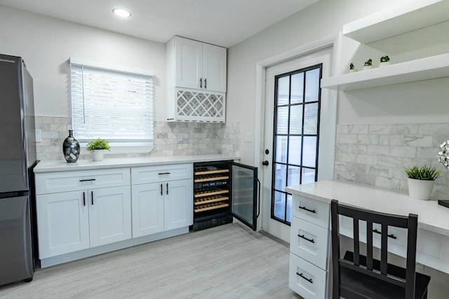 kitchen with light hardwood / wood-style floors, white cabinetry, fridge, and a healthy amount of sunlight