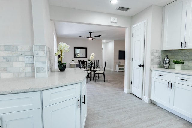 kitchen featuring backsplash, ceiling fan, light stone countertops, light hardwood / wood-style floors, and white cabinetry