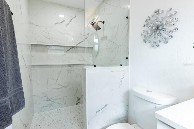 bathroom with toilet, vanity, and tiled shower