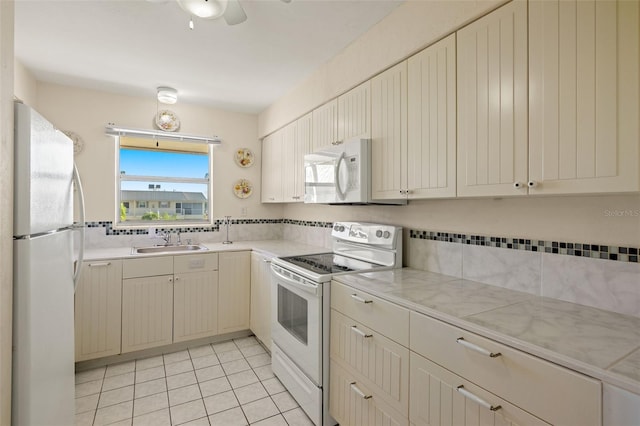 kitchen featuring light tile patterned floors, white appliances, ceiling fan, and sink