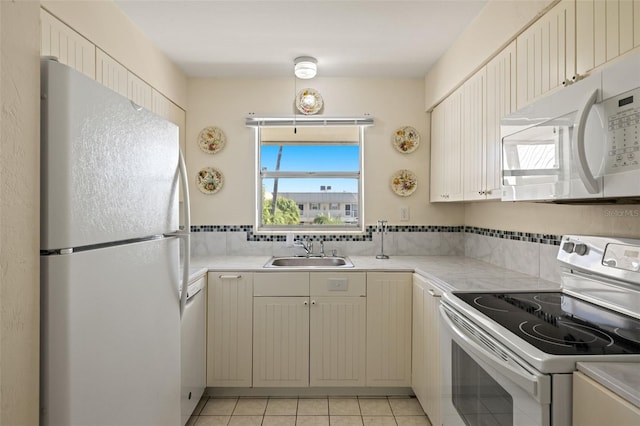 kitchen featuring sink, light tile patterned flooring, and white appliances