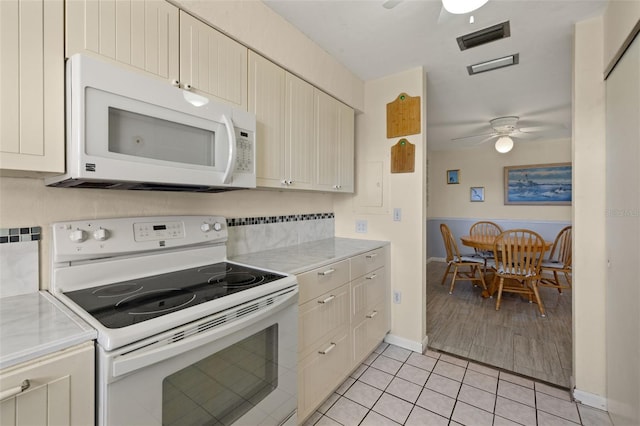 kitchen with ceiling fan, cream cabinets, light tile patterned floors, and white appliances