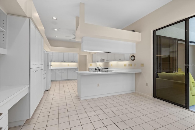 kitchen with sink, kitchen peninsula, ceiling fan, light tile patterned floors, and white cabinetry