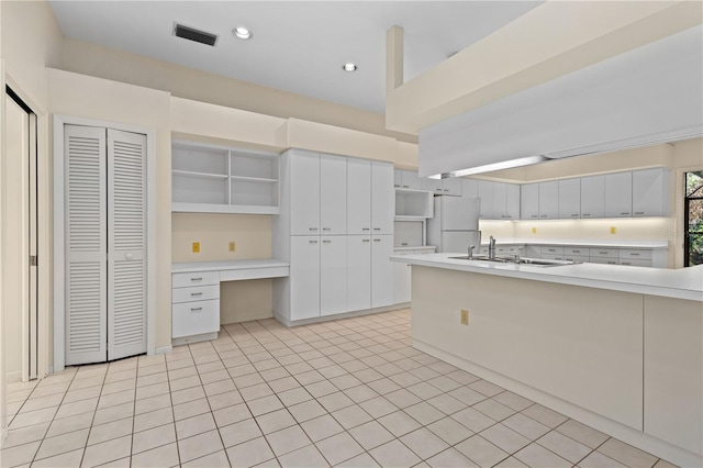 kitchen with white cabinets, light tile patterned floors, white fridge, and sink