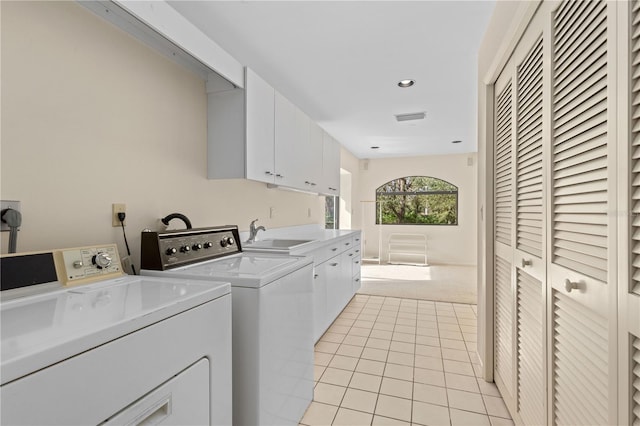 clothes washing area with cabinets, independent washer and dryer, light tile patterned floors, and sink