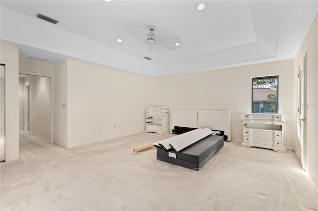 bedroom with ceiling fan, a raised ceiling, and light carpet