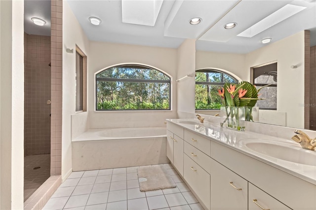 bathroom featuring tile patterned flooring, vanity, shower with separate bathtub, and a skylight