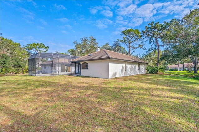 back of property with glass enclosure and a yard