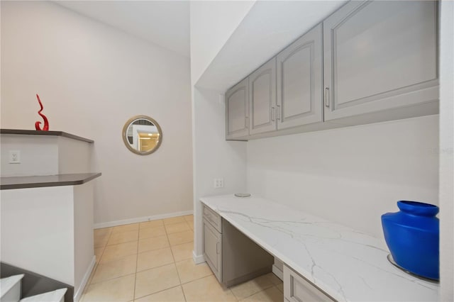 interior space with gray cabinets, light tile patterned flooring, and light stone counters