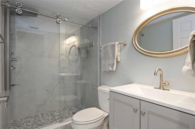 bathroom featuring a shower with door, vanity, and toilet