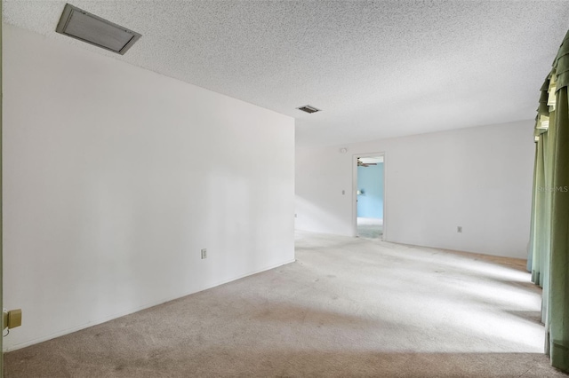 unfurnished room featuring light carpet, ceiling fan, and a textured ceiling