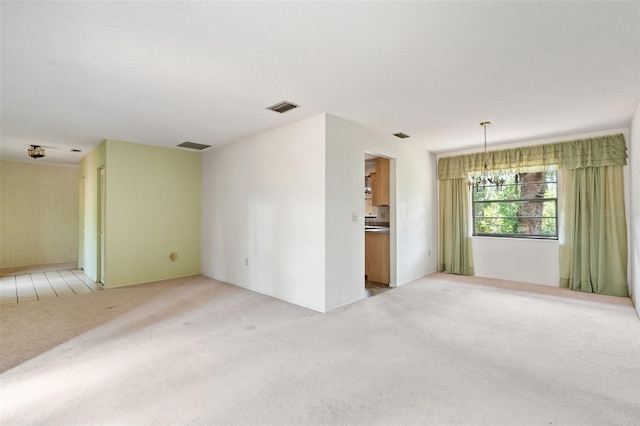 spare room featuring light carpet and a chandelier