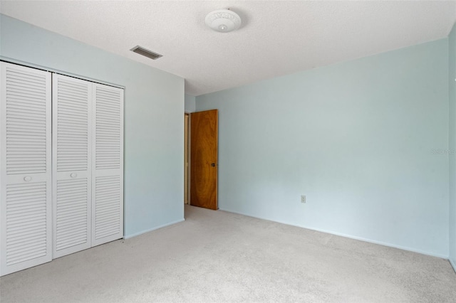 unfurnished bedroom featuring a closet, light colored carpet, and a textured ceiling