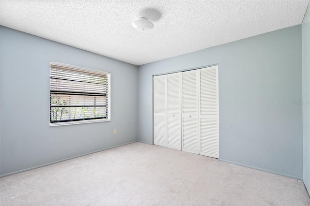 unfurnished bedroom with a textured ceiling, light colored carpet, and a closet