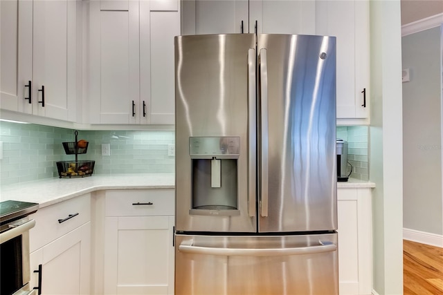 kitchen featuring decorative backsplash, white cabinetry, appliances with stainless steel finishes, and light hardwood / wood-style flooring