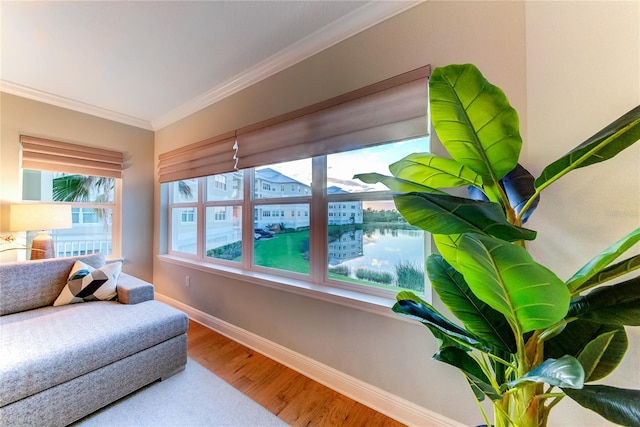 living area with a water view, hardwood / wood-style flooring, and crown molding