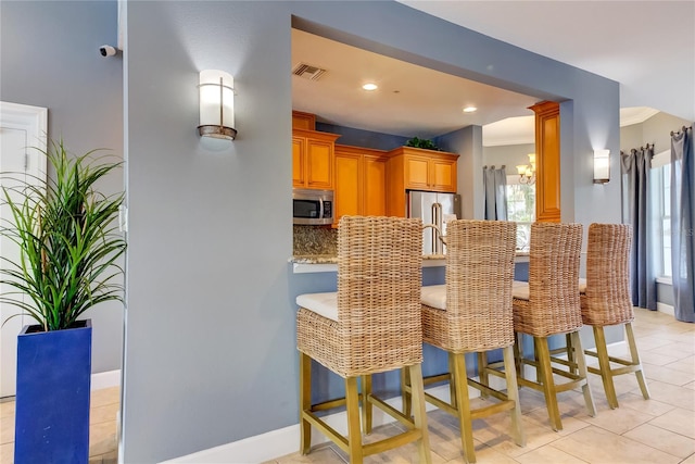 kitchen with backsplash, ornamental molding, a breakfast bar area, and appliances with stainless steel finishes