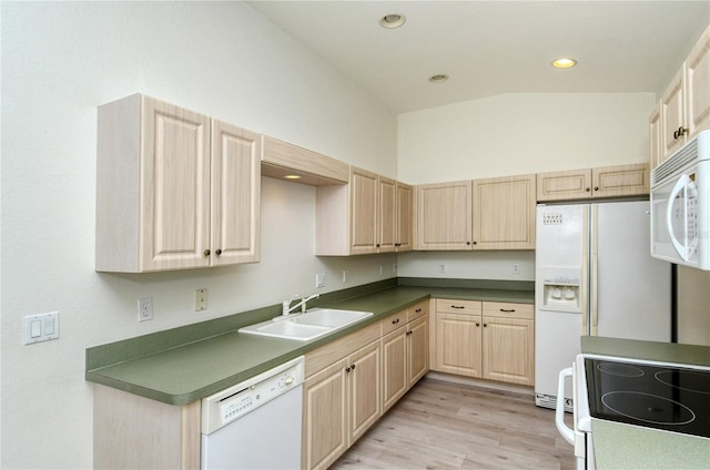 kitchen featuring sink, light hardwood / wood-style floors, vaulted ceiling, white appliances, and light brown cabinetry