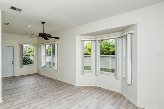 empty room featuring a wealth of natural light, ceiling fan, and light hardwood / wood-style floors