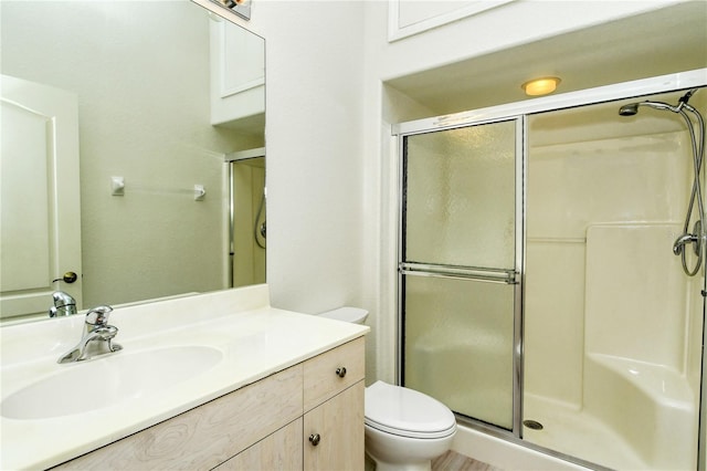 bathroom featuring vanity, toilet, and a shower with shower door