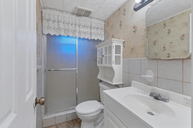 bathroom with vanity, tile patterned flooring, toilet, walk in shower, and tile walls