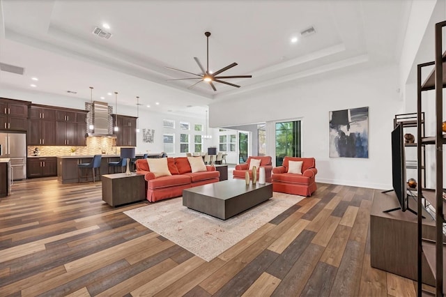 living room featuring dark hardwood / wood-style flooring, a tray ceiling, and ceiling fan