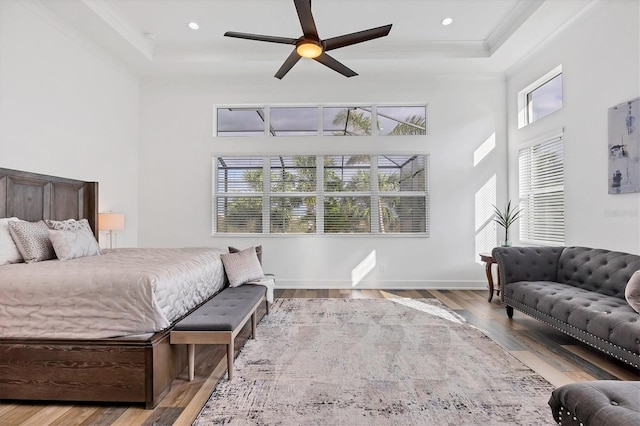 bedroom with ceiling fan, a towering ceiling, ornamental molding, and hardwood / wood-style flooring