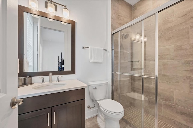 bathroom featuring vanity, a shower with shower door, and toilet