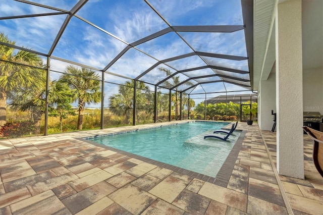 view of pool with a lanai, a grill, and a patio