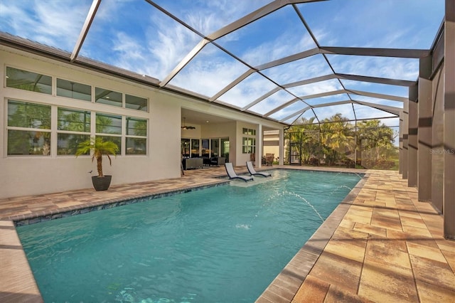 view of swimming pool featuring pool water feature, ceiling fan, a patio area, and a lanai