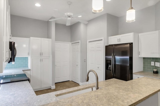 kitchen featuring ceiling fan, sink, stainless steel appliances, a towering ceiling, and white cabinets