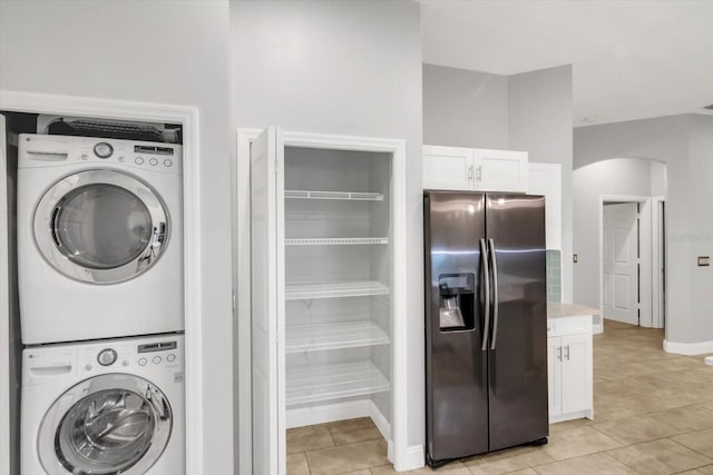 laundry room featuring light tile patterned floors and stacked washer and dryer