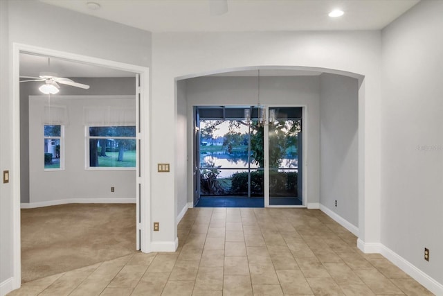 carpeted entrance foyer featuring ceiling fan with notable chandelier