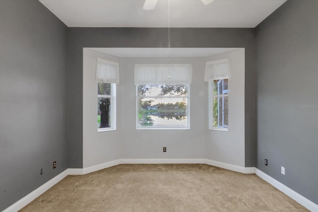 unfurnished room with light colored carpet and ceiling fan