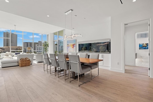 dining area with light hardwood / wood-style floors and an inviting chandelier