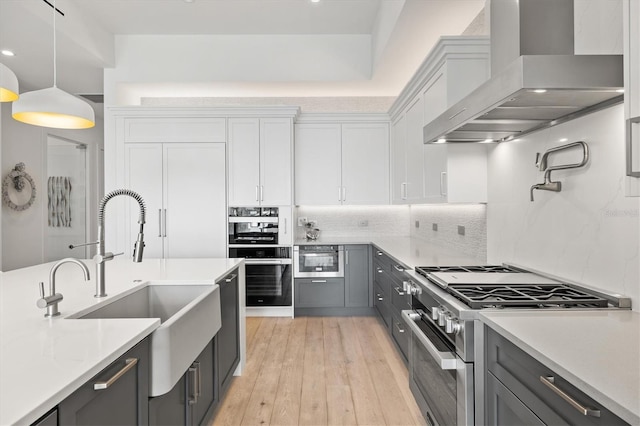 1335 2nd St Unit 301, Sarasota, FL 34236 - kitchen featuring wall chimney range hood, stainless steel range, gray cabinetry, white cabinetry, and light countertops