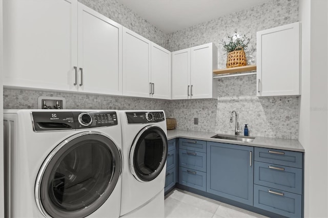 clothes washing area featuring sink, light tile patterned floors, cabinets, and independent washer and dryer