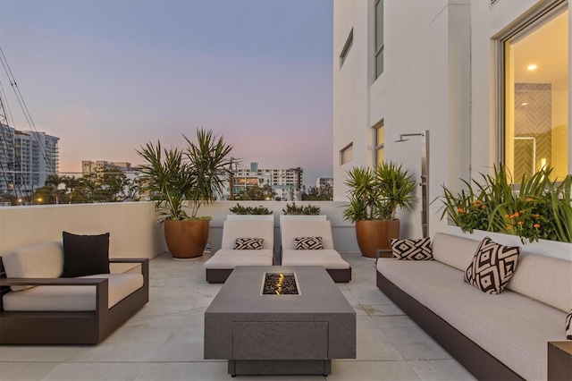 patio terrace at dusk with an outdoor living space with a fire pit