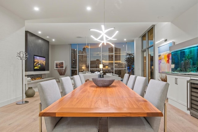 dining room with light wood-type flooring, wine cooler, and an inviting chandelier