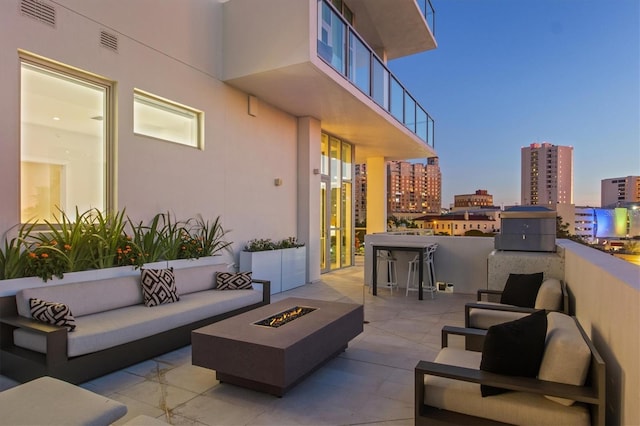 patio terrace at dusk featuring an outdoor living space with a fire pit