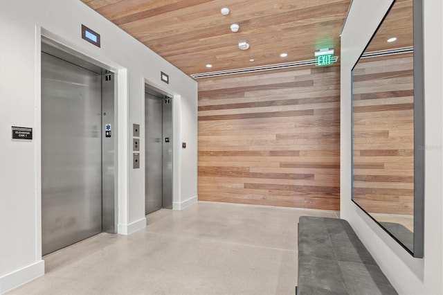 hall featuring elevator, wood walls, and wood ceiling