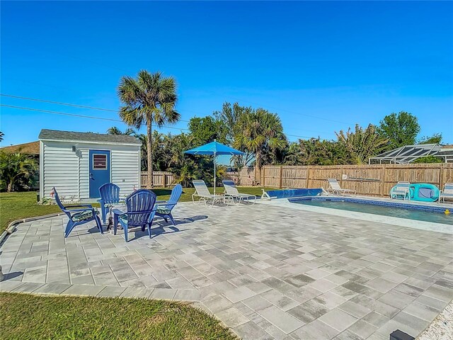 view of patio featuring a fenced in pool and a storage shed