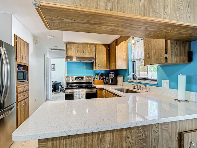 kitchen featuring kitchen peninsula, light stone countertops, sink, and stainless steel appliances