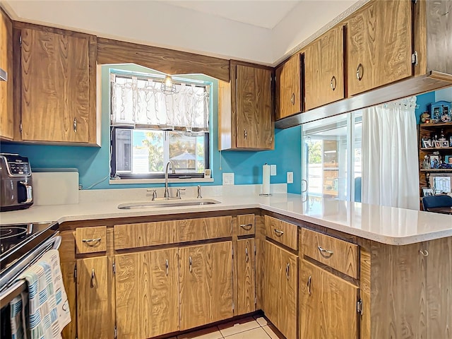 kitchen with kitchen peninsula, light tile patterned floors, and sink