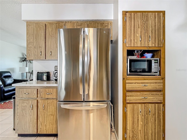 kitchen with appliances with stainless steel finishes, a textured ceiling, and light tile patterned floors