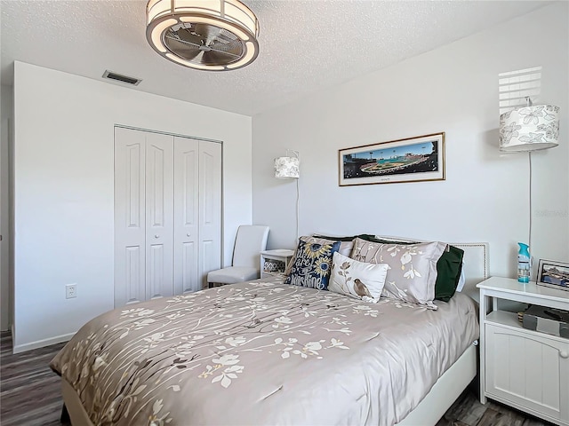 bedroom featuring a closet, dark wood-type flooring, and a textured ceiling